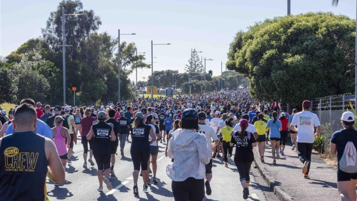 Large crowd taking part in a fun run on a sunny day, showing community fundraising in action.