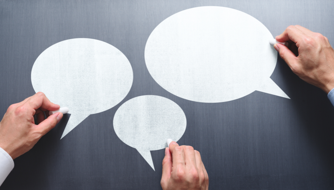 Speech bubbles being drawn on a board, representing communication and inclusive workplace conversations.