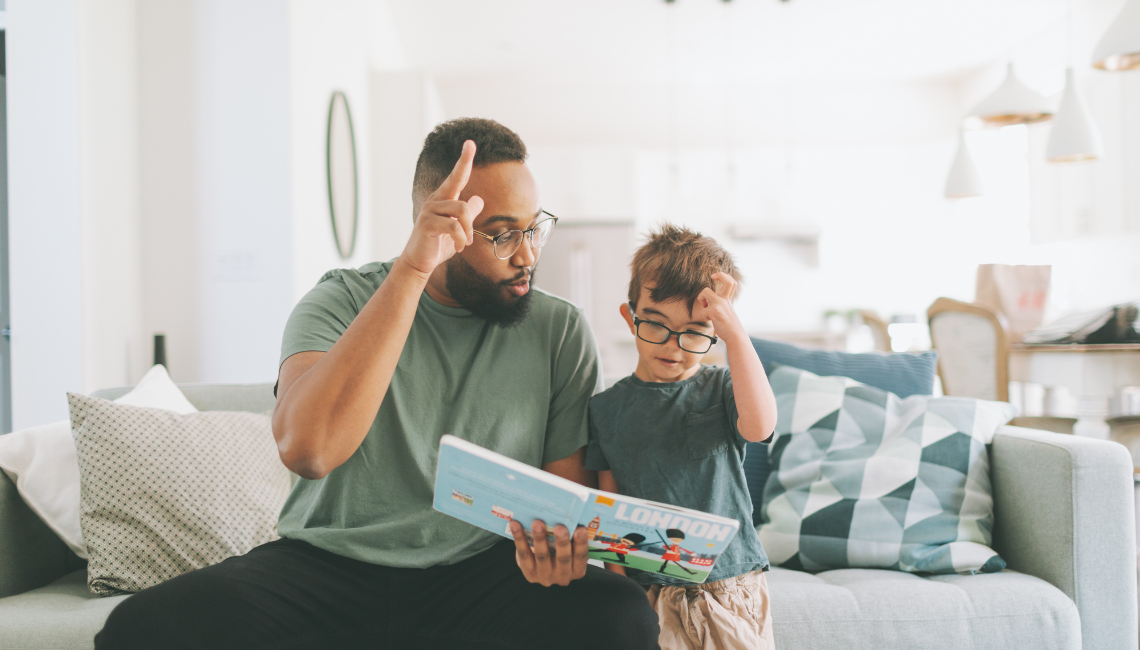 Adult and child read a book together while signing at home, showing everyday communication and learning in NZSL.