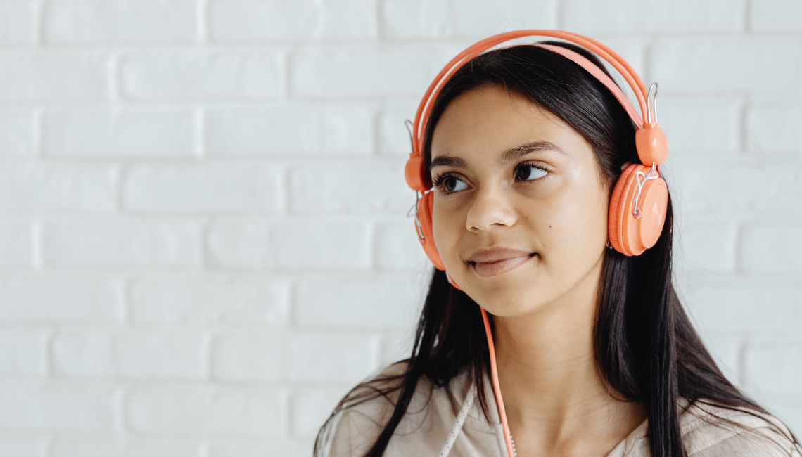 Young female teen with peach headphones on her ears