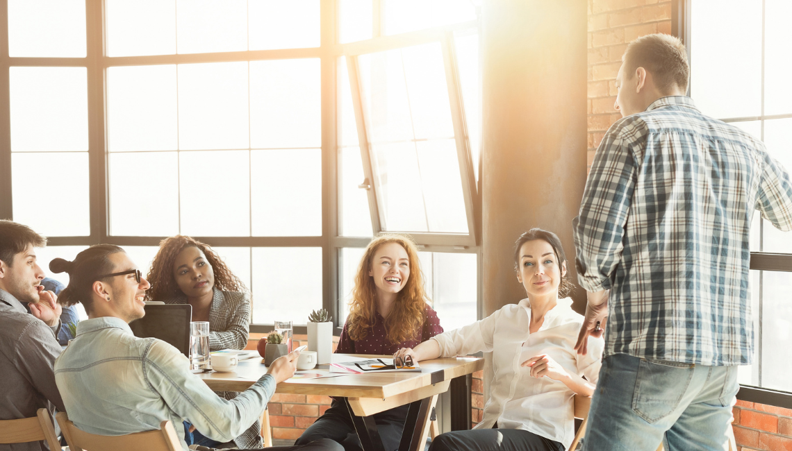 Colleagues gathered around a table during a workplace discussion, representing team participation and inclusion.
