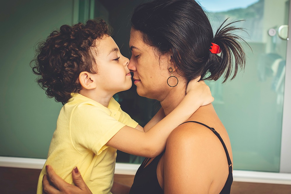 Young child embraces an adult woman face to face, showing close connection and support in a hearing health context.