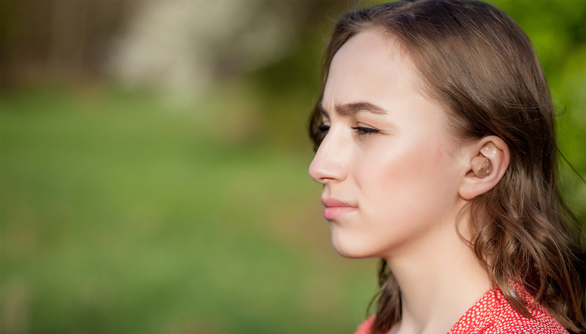 A young woman in deep thoughts standing up in a park