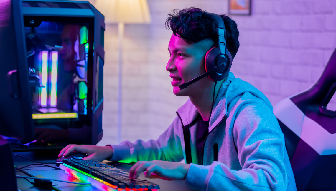 Teenager wearing a gaming headset at a computer during online play.