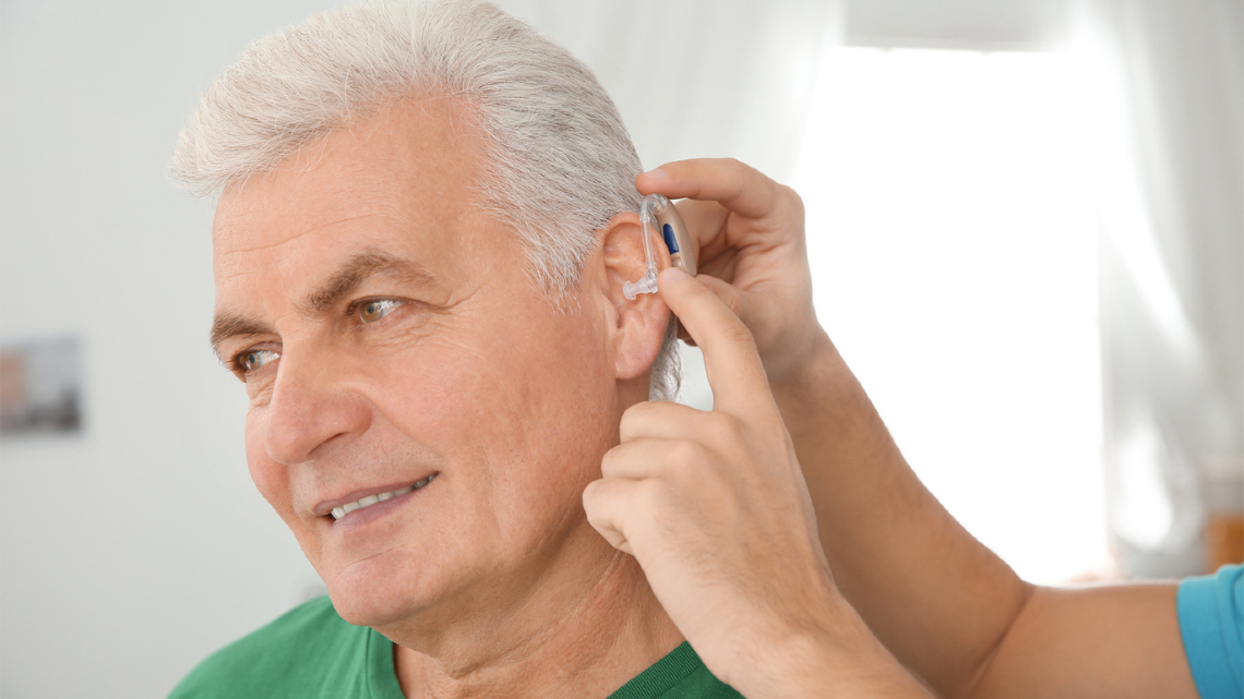 Man having a hearing aid fitted, highlighting practical support for hearing and daily life.