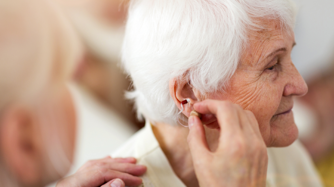 Older woman having her hearing aid fitted, highlighting practical hearing support for everyday life.