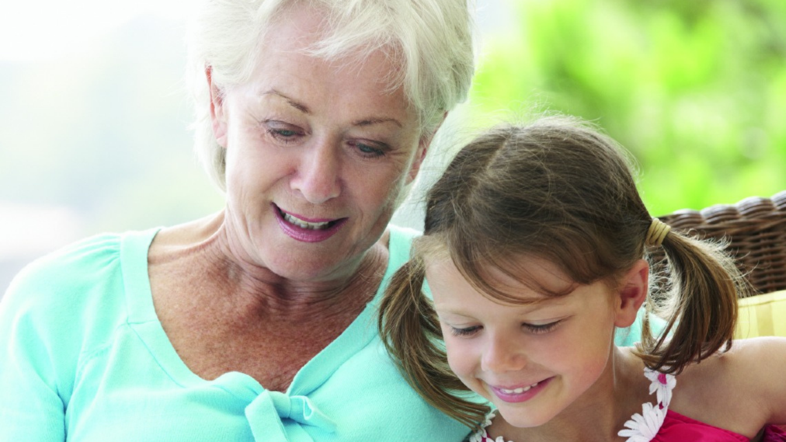 Older woman and young girl reading together, showing care, connection, and support across generations.