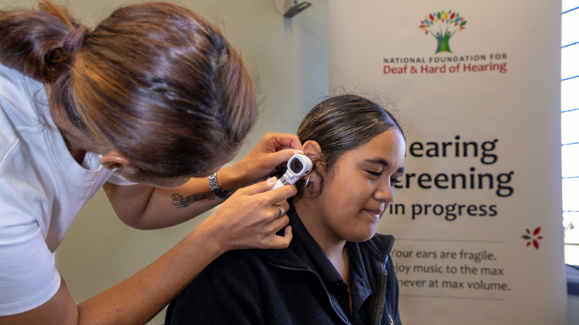 Staff member checks a student’s ear during a school hearing screening.
