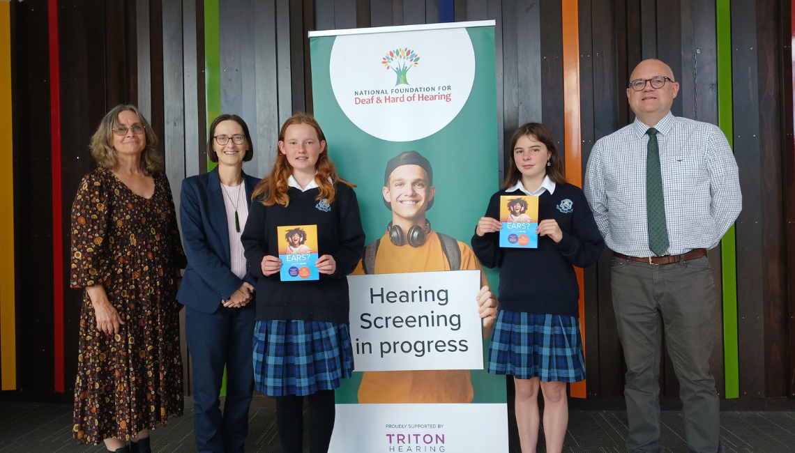 Two female students at a school screening and holding the Love Your Ears brochure