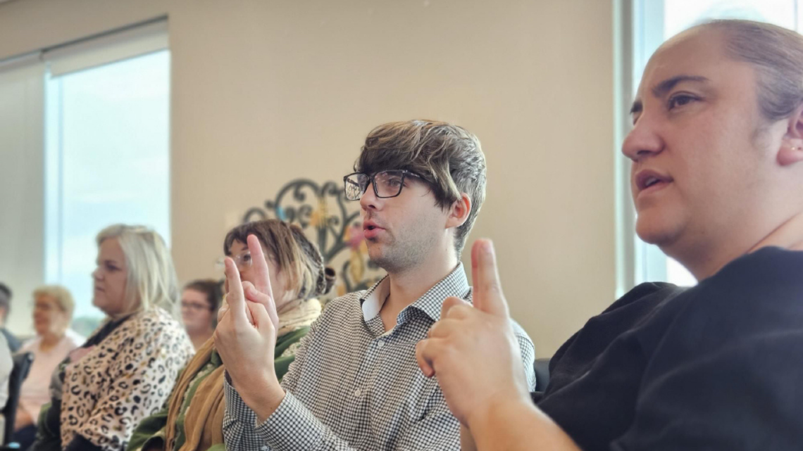 Participants using sign language during a workplace training session.