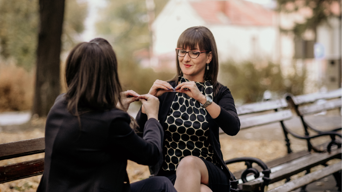 Two women signing to each other at the park.