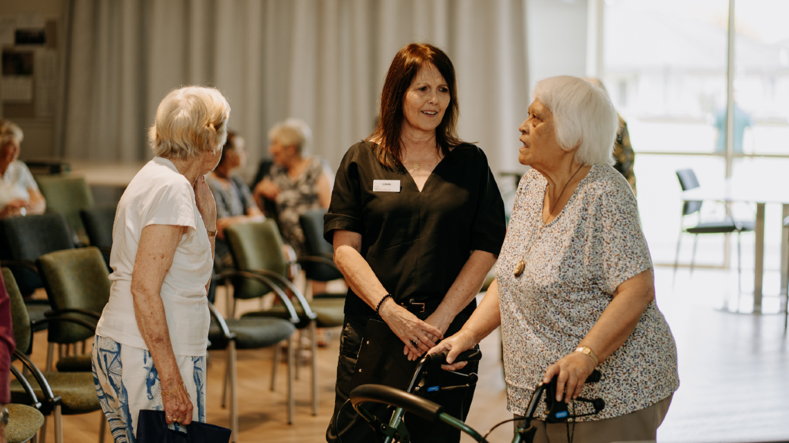 Staff member talking with older community members at an indoor event.