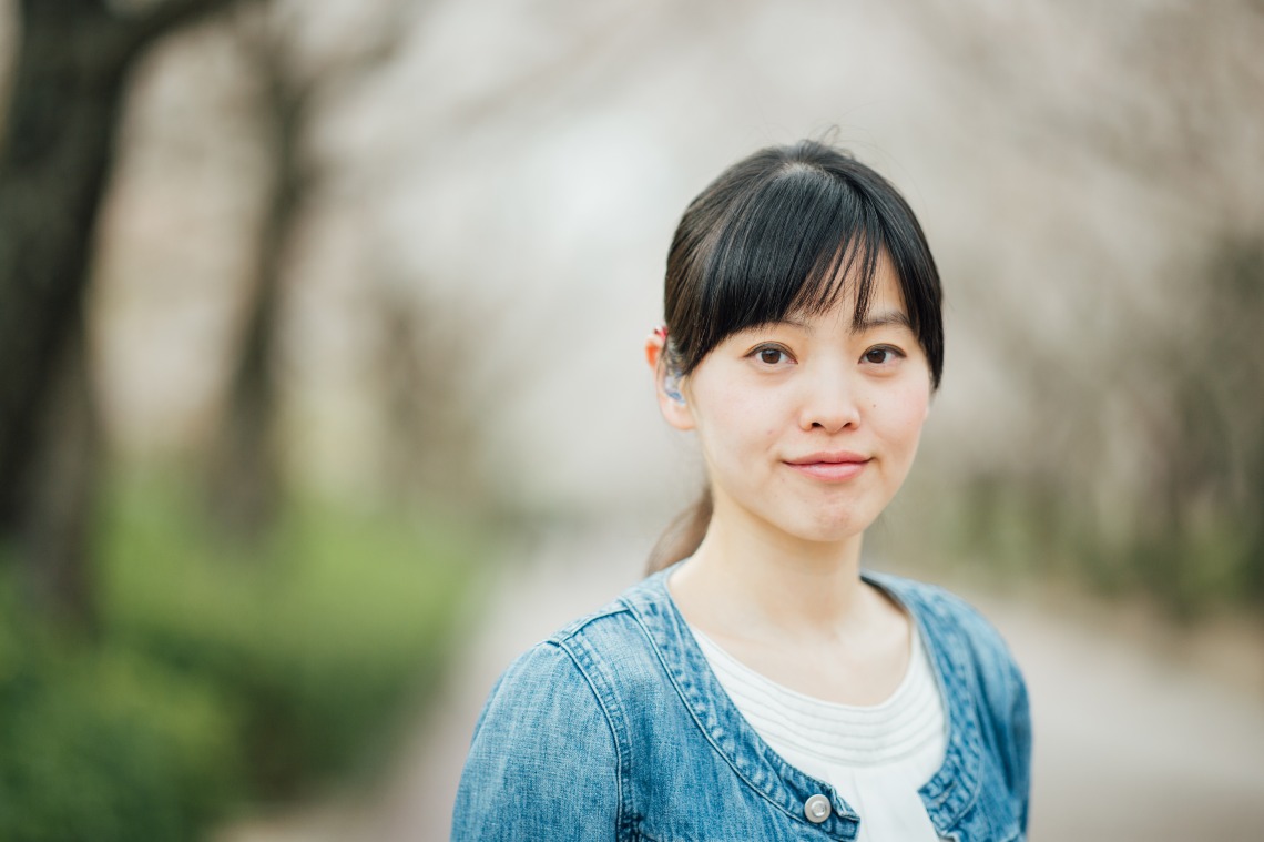Young woman outdoors wearing a hearing device, representing inclusion and everyday hearing health support.