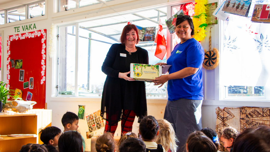 Two adults present a Sound Monkey resource box to a classroom of young children.