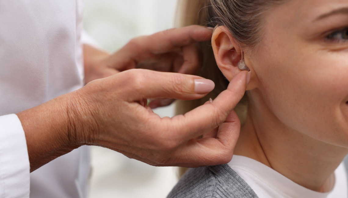A young woman with blond hair getting fitted with hearing aids