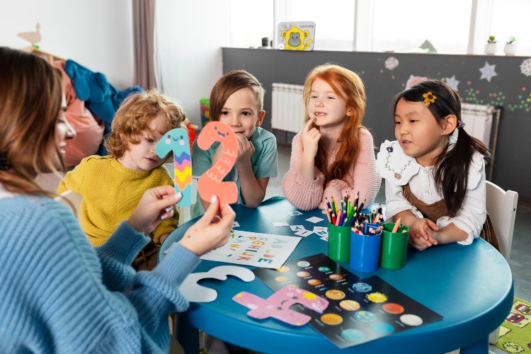 Preschool teacher holding numbers in her hands. There is a Sound Monkey in the background