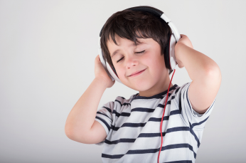 Young male kid with black hair wearing white headphones