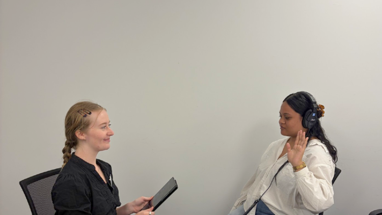 Two women in conversation during a one-to-one hearing support session, seated together in a calm clinic setting.