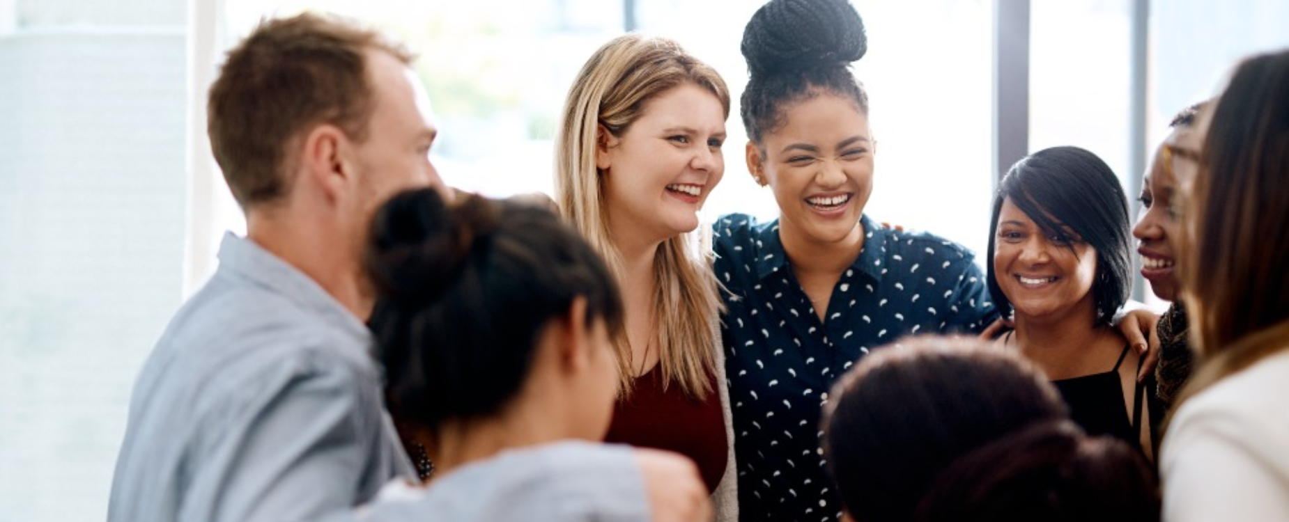 Group of adults standing together and smiling during a conversation.