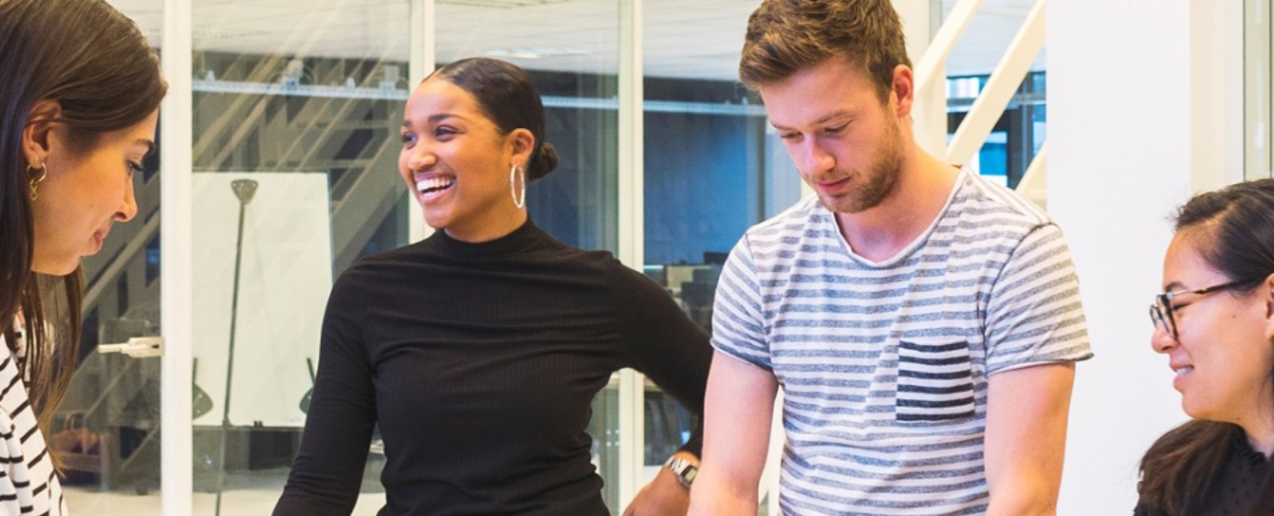 Team members smiling and collaborating in a modern office meeting, reflecting a welcoming and inclusive workplace culture.