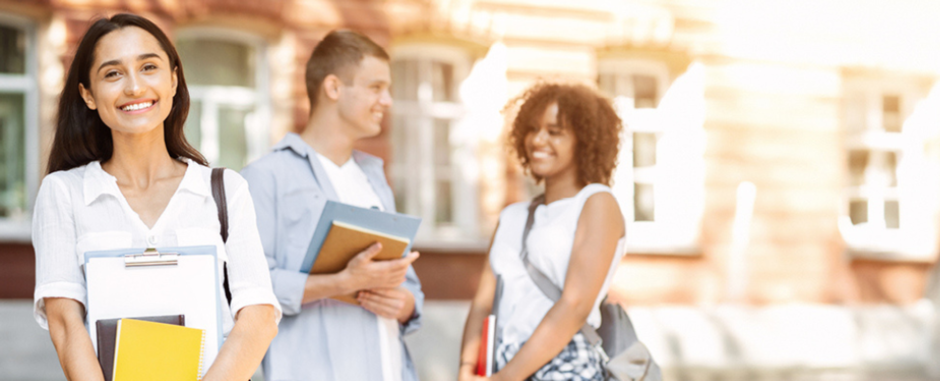 Smiling students holding books and notebooks on campus, representing education opportunities and academic success.