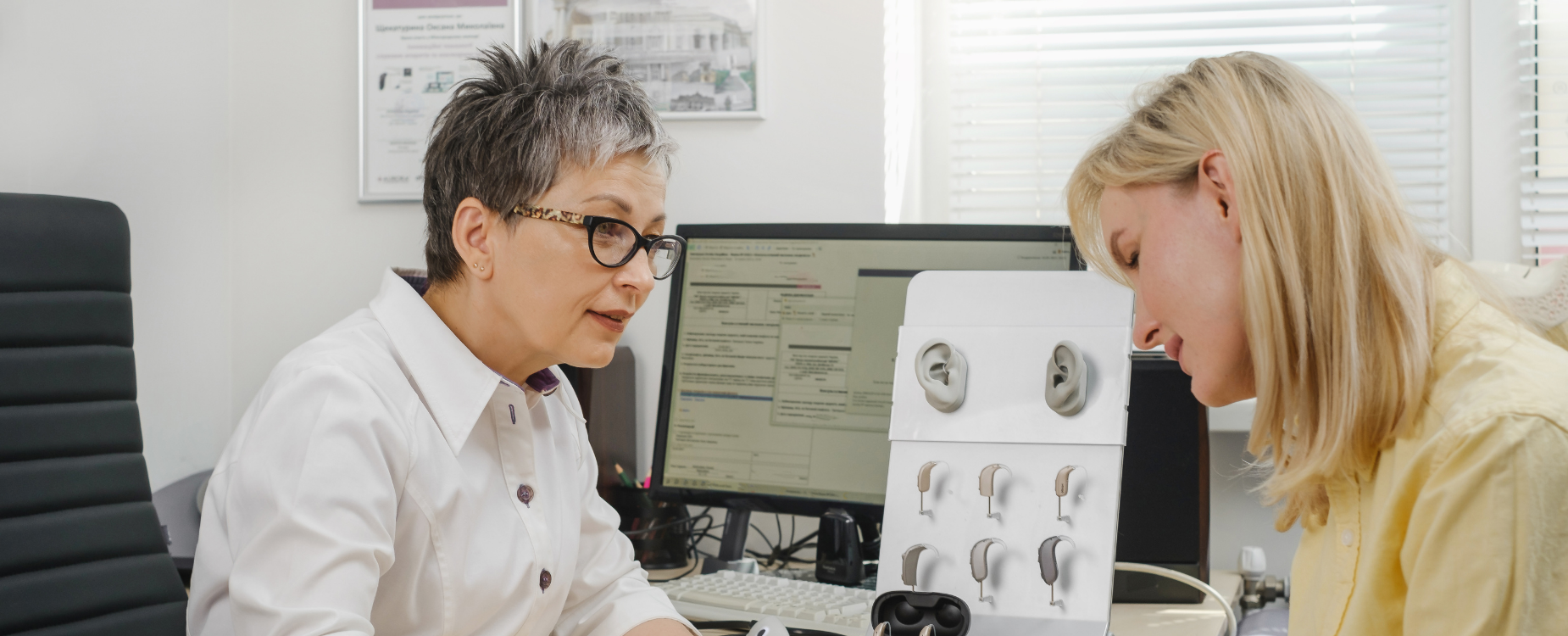 A lady with blond hair getting information about hearing aids with her audiologist sitting in front of her.