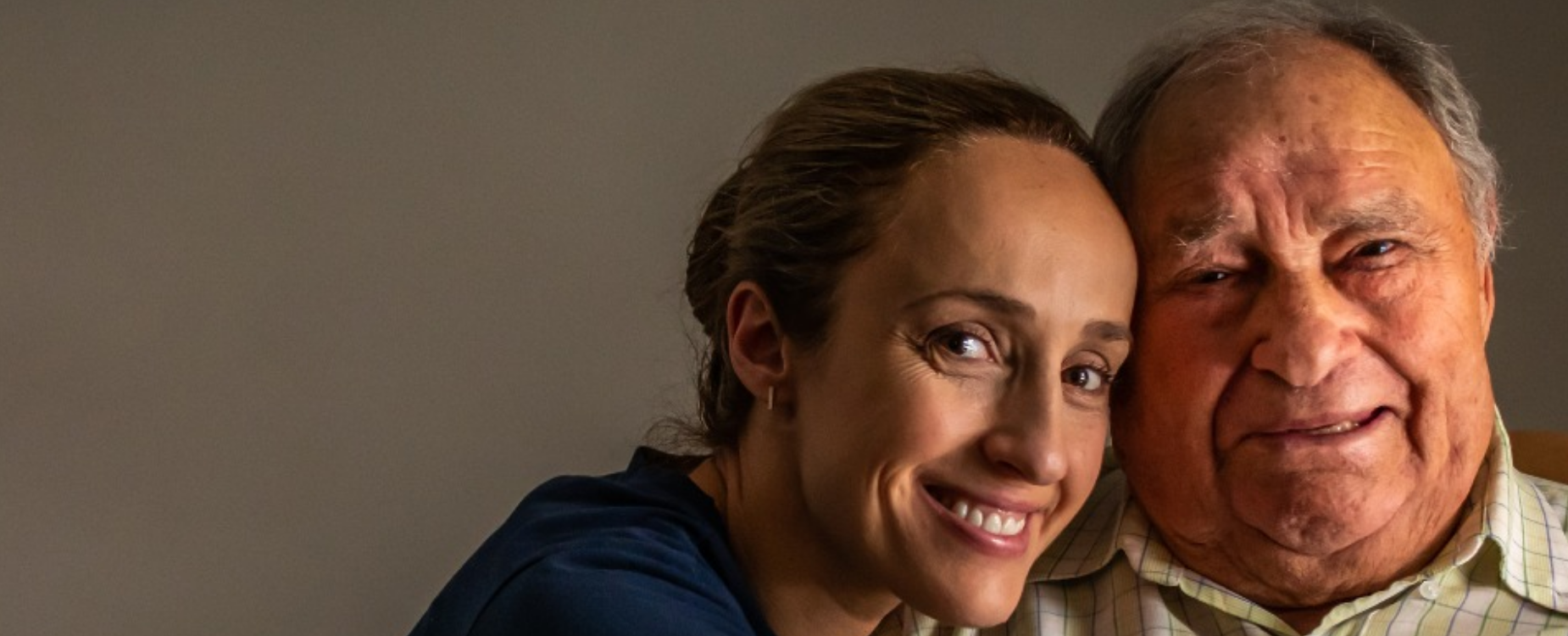 Woman and older man smiling closely together, showing warmth, care, and personal connection.