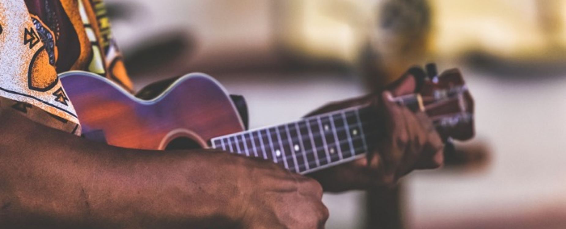 Close-up of hands playing a ukulele, reflecting Pasifika culture and community connection.