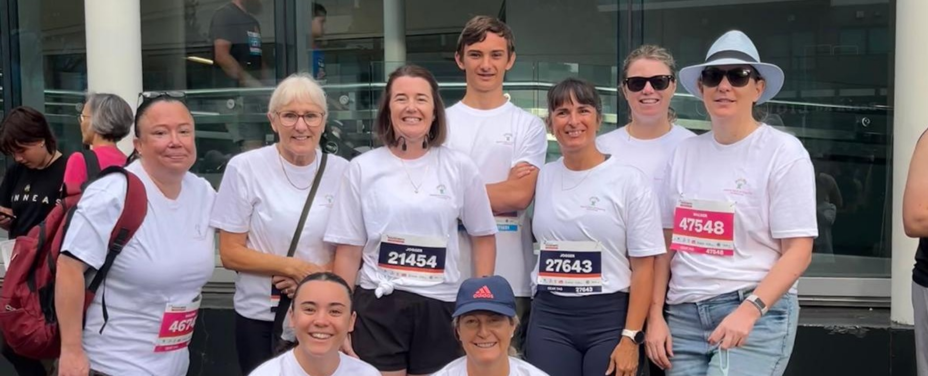 Group of previous Round the Bays participants in event T-shirts, smiling together before the run.