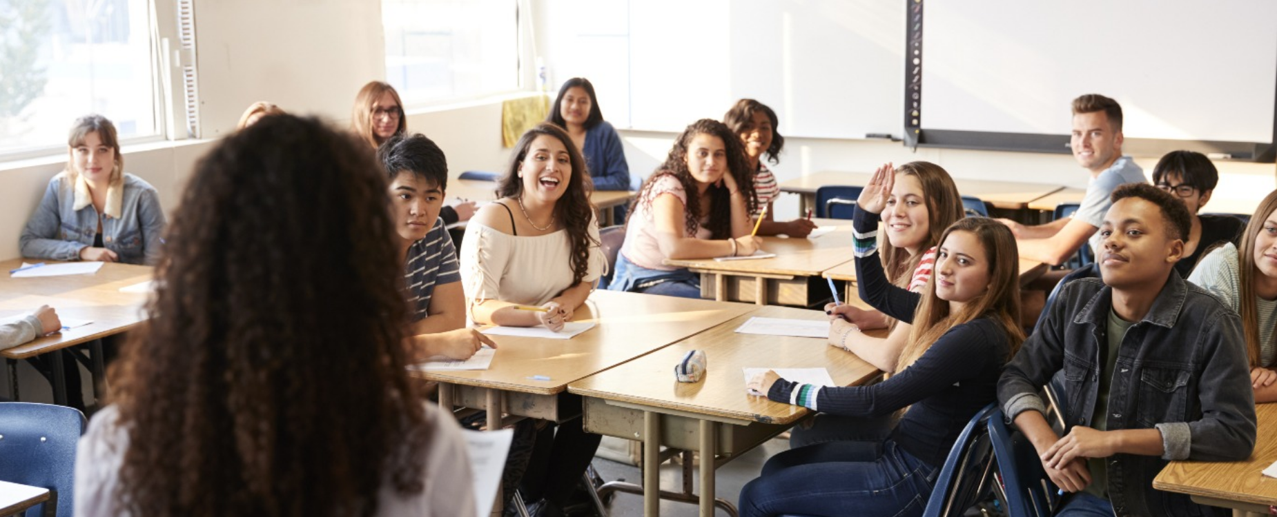 Smiling student sitting in a classroom looking at the teacher.