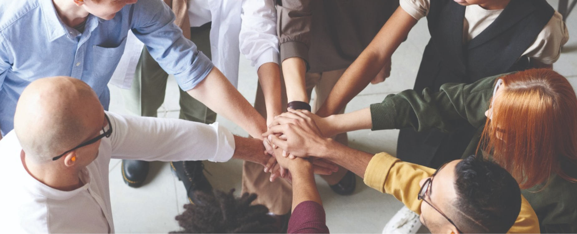 Group of people stacking their hands together, representing shared commitment and teamwork in support of payroll giving.